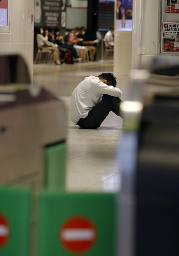 7일 오후 일본 수도권 일대에 강진이 발생한 가운데 도쿄 역에서 한 남성이 바닥에 앉아 있다. 이날 지진의 영향으로 신칸센이나 지하철 등의 운행이 일시 중단돼 시민들이 귀가에 어려움을 겪었다./교도연합뉴스