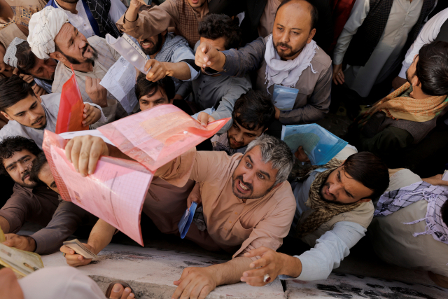 아프가니스탄 수도 카불의 여권 사무소 앞에서 여권을 발급받으려는 주민들이 앞다퉈 신청서를 내밀고 있다./로이터 연합뉴스