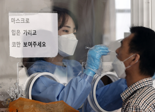 지난 11일 오전 서울역 광장 임시선별검사소에서 의료진이 검사소를 찾은 시민의 코로나 19 검사를 하고 있다./연합뉴스