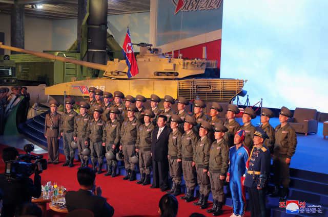 지난 12일 김정은 당 총비서가 국방발전전람회장을 참관하고 관계자들과 기념사진을 찍고 있다. 가장자리의 파란색 전신 타이츠를 입은 남성의 모습이 해외 SNS에서 화제가 되고 있다. /연합뉴스