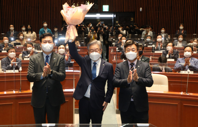 이재명 대선 후보가 15일 오전 서울 국회에서 열린 더불어민주당 의원총회에 참석해 꽃다발을 들어올리며 인사하고 있다. /권욱 기자