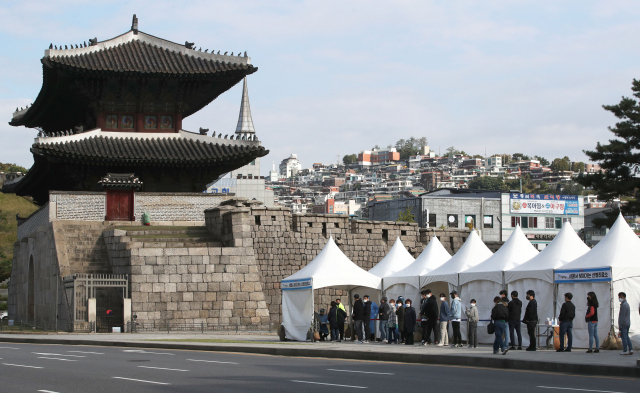 지난 18일 오전 서울 종로구 흥인지문 옆에 설치된 찾아가는 선별검사소에서 코로나19 집단감염이 발생한 동대문 인근 시장 종사자들이 검사를 받기 위해 대기하고 있다./연합뉴스