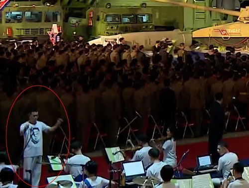 지난 11일 열린 국방발전전람회 '자위-2021'에서 음악 연주를 지휘하는 북한 지휘자의 티셔츠에 김정은 북한 국무위원장 얼굴이 그려져 있다. /연합뉴스