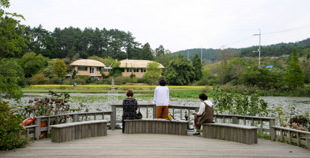 천리포수목원을 찾은 여행객들이 의자에 앉아 민병갈기념관을 바라보고 있다.