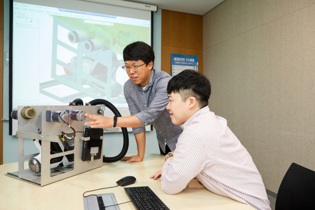 정우현(왼쪽) 삼성디스플레이 중소형기술혁신팀 프로와 박광돈 프로가 자신들의 아이디어로 구체화된 크레인 클리닝 로봇을 살펴보고 있다./사진제공=삼성디스플레이