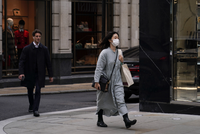 지난 19일(현지시간) 영국 런던에서 마스크를 쓴 여성이 길을 걸어가고 있다. /AP연합뉴스