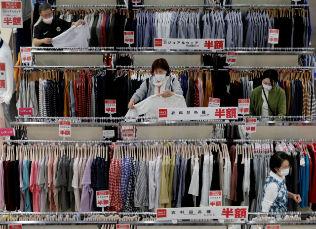 지난해 5월 일본 지바에서 코로나바이러스병(COVID-19)이 창궐한 가운데 쇼핑몰이 다시 문을 열자 마스크를 쓴 쇼핑객들이 일본 슈퍼마켓 그룹 에이온(Aeon)의 쇼핑몰에서 옷을 고르고 있다./로이터연합뉴스