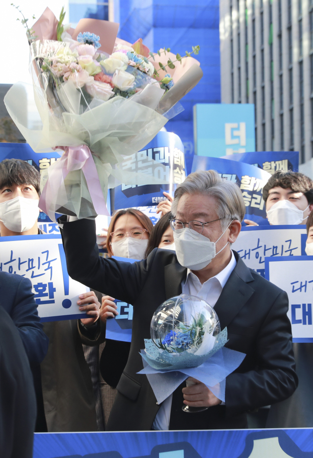 이재명 더불어민주당 대선 후보가 지난 27일 여의도 민주당사에서 꽃다발을 흔들고 있다. /연합뉴스