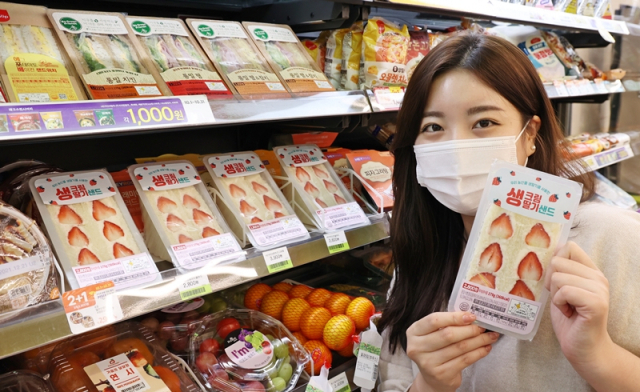CU 모델이 다음 달 2일부터 포켓 CU 앱에서 예약 판매를 시작하는 생크림 딸기 샌드위치를 소개하고 있다./사진 제공=CU
