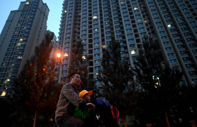 한 남성이 어둠에 쌓인 중국 베이징의 헝다 아파트단지 앞을 지나가고 있다. /AFP연합뉴스