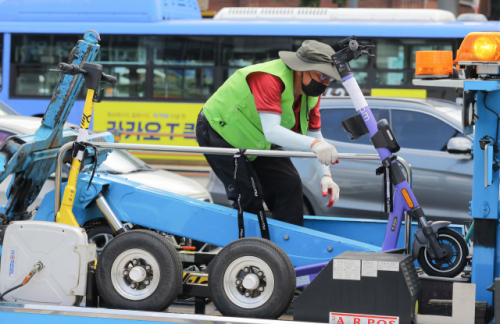 지난 7월 서울 송파구 가락시장역 인근에서 송파구청 관계자가 불법 주정차된 전동 킥보드를 견인하고 있다./이호재 기자