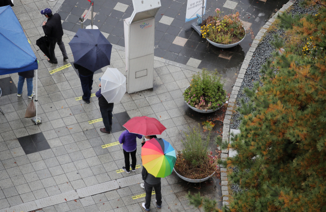 코로나19 선별검사소에서 우산을 쓴 시민들이 검체 검사를 기다리고 있다./연합뉴스