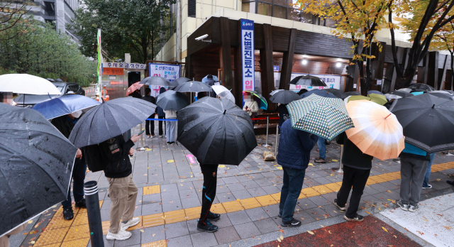 8일 오전 서울 송파구 보건소 코로나19 선별검사소에서 시민들이 검사를 받기 위해 우산을 쓴 채 차례를 기다리고 있다./연합뉴스