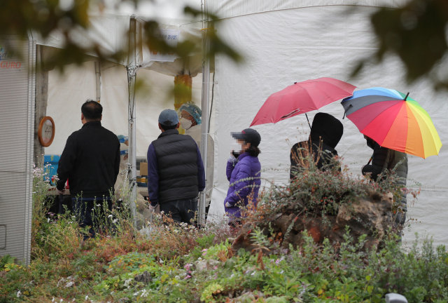 8일 오후 서울 구로역에 마련된 코로나19 선별검사소에서 우산을 쓴 시민들이 검체 검사를 기다리고 있다./연합뉴스