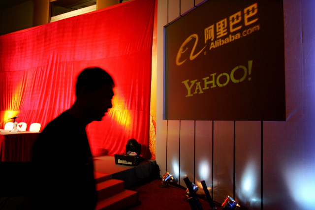 한 남자가 베이징의 차이나월드호텔에서 열린 회사들의 공동 기자회견에 앞서 야후와 알리바바 로고가 표시된 화면을 지나가고 있다. /AP연합뉴스