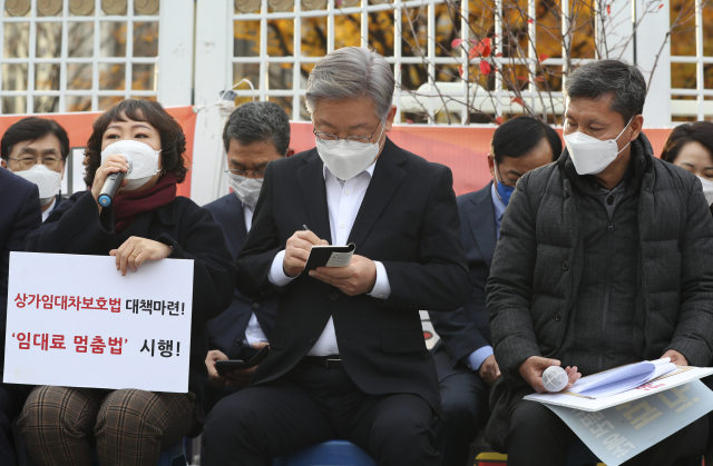 이재명(왼쪽 두번째) 더불어민주당 대선 후보가 15일 정부서울청사 앞에서 열린 지역화폐·골목상권 살리기 운동본부 농성 현장을 방문해 유경희 포방터시장 상인회장의 말을 받아적고 있다. / 권욱 기자