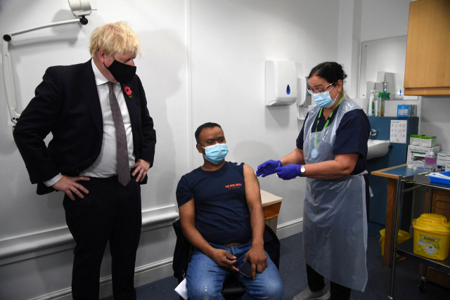 보리스 존슨(왼쪽) 영국 총리가 15일 런던의 한 백신 센터를 방문해 부스터샷을 맞는 한 남성을 지켜보고 있다. /AFP연합뉴스