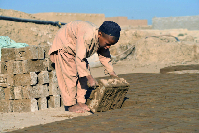 11일(현지시간) 아프가니스탄 남부 칸다하르에서 한 어린이가 형틀을 이용해 진흙 벽돌을 만들고 있다. /연합뉴스