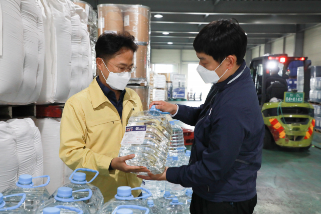 김정우(왼쪽) 조달청장이 차량용 요소수 생산기업 한일화학공사를 방문해 요소수를 살펴보고 있다. 사진제공=조달청