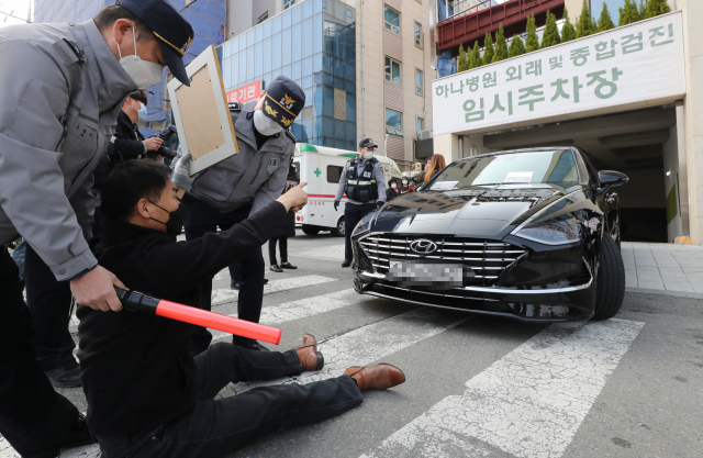 코로나19백신피해자가족협의회(코백회) 회원들이 19일 충북 예방접종 위탁의료기관인 청주시 하나병원 앞에서 정은경 질병관리청장의 차량을 막고 면담을 요구하고 있다./연합뉴스