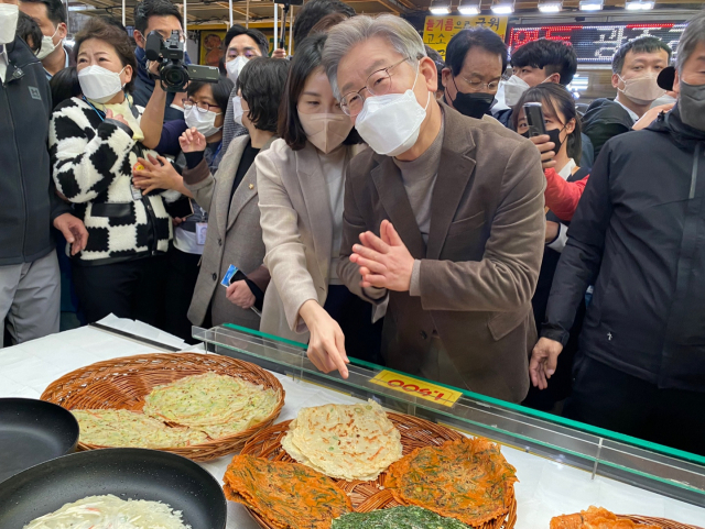 이재명 더불어민주당 대선 후보와 부인 김혜경씨가 21일 충북 청주 육거리시장을 찾아 전 가게에서 김치전을 구입하고 있다. / 주재현 기자