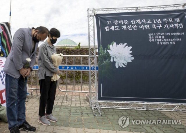 10월 12일 오후 국회 앞에서 열린 ‘고 장덕준 산재사고 1년 추모 및 법제도 개선안 마련 촉구 기자회견’에서 고 장덕준 씨의 유가족이 묵념하고 있다. / 연합뉴스