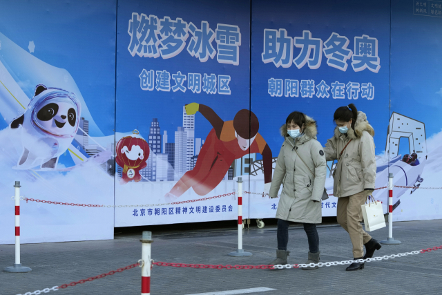 지난 22일 중국 베이징 시민들이 올림픽 홍보판 옆을 지나가고 있다. 베이징 올림픽을 준비한다며 베이징시의 방역 조치가 최대한도로 강화됐다. /AP연합뉴스