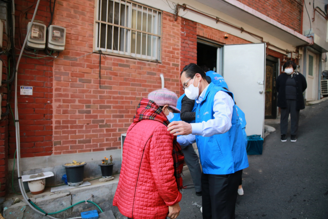 지난 29일 창신 2동에서 진행된 김장김치 전달 행사에서 김정기(오른쪽) 우리카드 대표가 주민에게 목도리를 걸어주고 있다. 사진 제공=우리카드