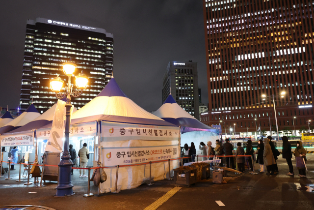 30일 밤 서울역 광장에 마련된 중구 임시선별검사소에 퇴근 시간 이후에도 시민들이 줄을 서서 검사 순서를 기다리고 있다. /연합뉴스