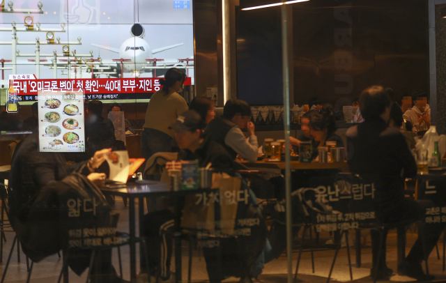 지난 1일 서울 중구의 한 식당에서 시민들이 식사를 하고 있는 가운데 코로나19 새 변이 바이러스인 ‘오미크론’에 감염된 사례가 국내에서 처음으로 확인됐다는 뉴스가 대형 화면에서 나오고 있다./연합뉴스