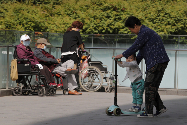 중국 베이징의 한 공원에서 할머니가 손주를 돌보고 있다. /AP연합뉴스