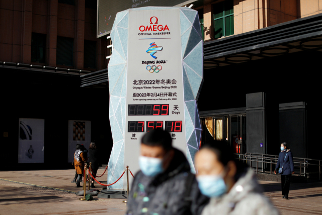 미국이 베이징 동계 올림픽에 대한 '외교적 보이콧' 방침을 밝힌 가운데 7일 중국 수도 베이징에서 올림픽이 59일 앞으로 다가왔음을 알리는 카운트다운 시계 앞을 마스크를 쓴 행인들이 지나가고 있다. /로이터연합뉴스