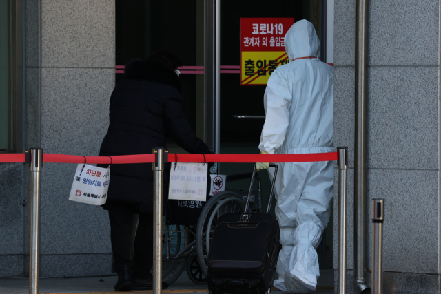 13일 오후 서울 은평구 서울특별시립 서북병원에서 한 코로나19 환자가 의료진의 도움을 받아 입원하고 있다. 이날까지 수도권에서 병상 배정을 기다리는 코로나19 환자 수는 1,500명 이상이다./연합뉴스