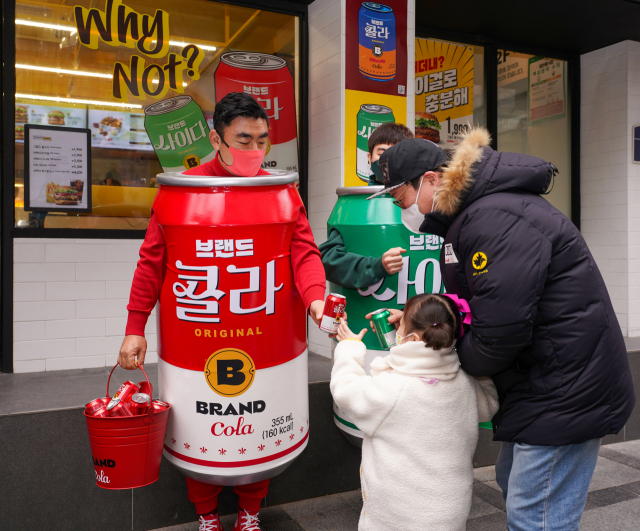 송현석(왼쪽) 신세계푸드 대표이사가 14일 특별 제작한 콜라맨 의상을 착용하고 제품을 나눠주고 있다. /사진 제공=신세계푸드