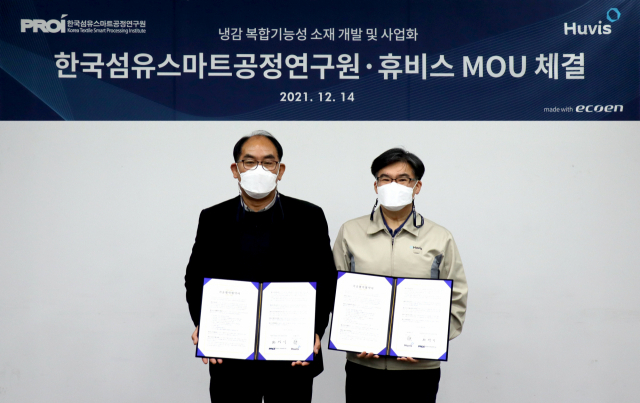 박성윤(오른쪽) 휴비스 R&D 센터장과 전성기 한국섬유스마트공정연구원장이 14일 열린 업무협약 체결식에서 협약서를 들어보이고 있다./사진제공=휴비스
