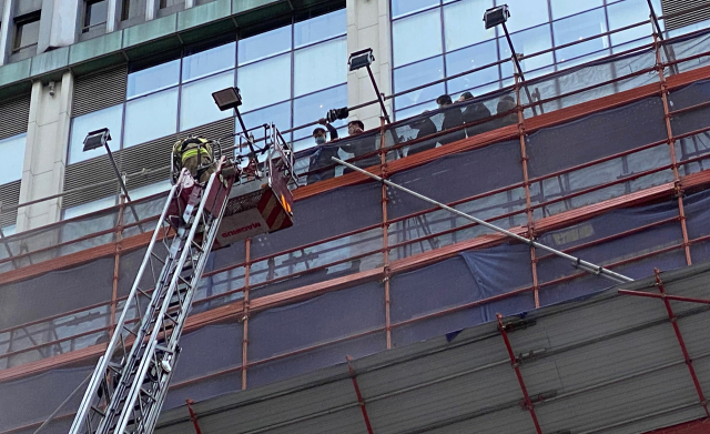 홍콩 코스웨이베이 세계무역센터 화재 현장에서 15일 한 소방관이 크레인을 이용해 건물에 갇힌 시민들을 구조하고 있다. /AP연합뉴스