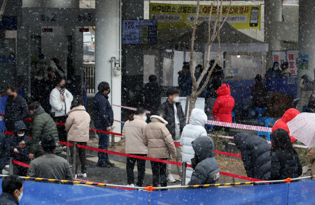 17일 오전 광주 서구보건소 선별진료소에서 코로나19 검사를 받으려는 시민들이 내리는 눈을 맞으며 줄 서 있다./연합뉴스