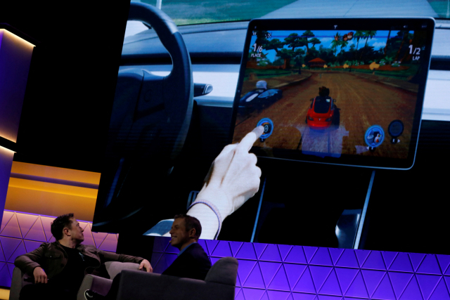 일론 머스크(왼쪽) 테슬라 CEO가 지난 2019년 E3 게이밍 컨벤션에서 테슬라의 비디오 게임을 소개하는 영상물을 지켜보고 있다. /로이터연합뉴스