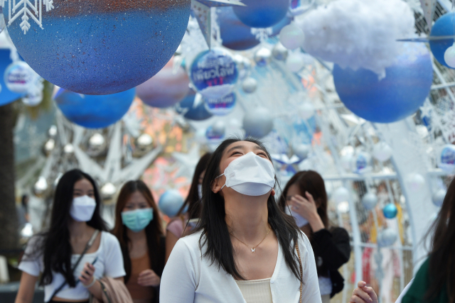 태국 방콕 시민들이 24일(현지시간) 마스크를 쓴 채 크리스마스 장식 아래를 걷고 있다./신화연합뉴스