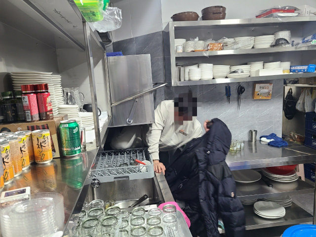 보이스피싱 지명수배자 A씨가 주방 식기세척기 밑에 숨어있다가 적발돼 나오는 모습./수서경찰서 제공