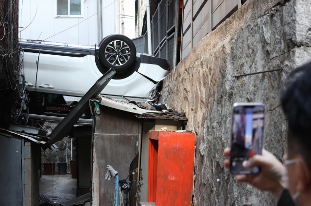 6일 오전 서울 중구의 한 주차장 건물에서 차량이 추락해 걸어가던 시민이 현장을 지켜보고 있다. /연합뉴스