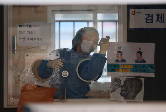 코로나19 임시 선별검사소에서 의료진이 유리벽에 붙은 얼음 조각을 긁어내고 있다. /연합뉴스