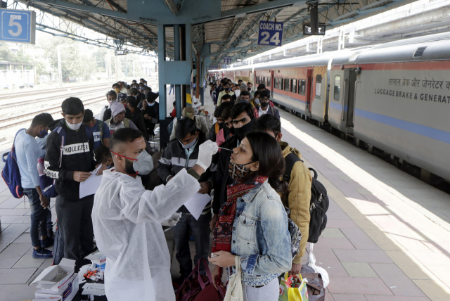 인도의 한 의료인이 12일(현지시간) 뭄바이의 한 기차역에서 열차에서 내린 승객들을 대상으로 코로나19 테스트를 위해 검체를 채취하고 있다. /AP연합뉴스