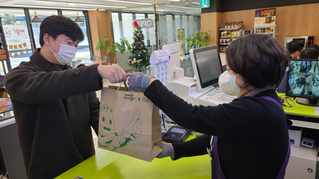 CU제주그랜드조선호텔점에서 점원이 고객에게 친환경 종이봉투로 상품을 전달하고 있다./사진 제공=BGF리테일