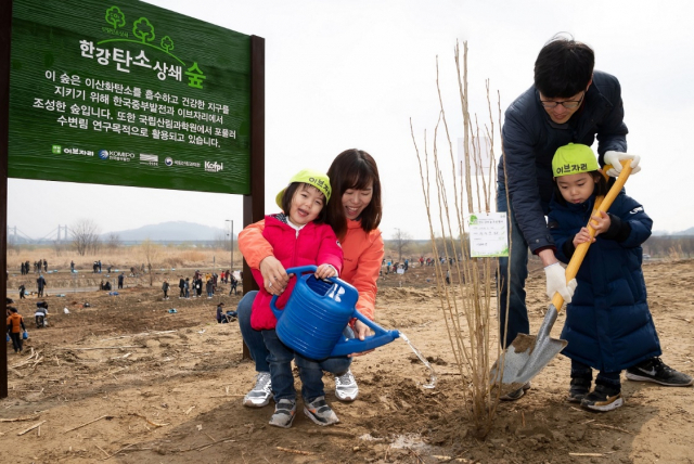 이브자리가 탄소흡수원 증진을 목적으로 개최한 ‘한강 탄소상쇄숲 조성행사’에 참가한 한 가족이 서울 강서 한강공원 일대에 나무를 심고 있다. / 사진제공=이브자리