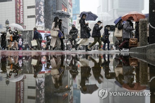 일본 도쿄 도심에서 눈이 내리는 가운데 행인들이 우산을 쓰고 이동하고 있다.