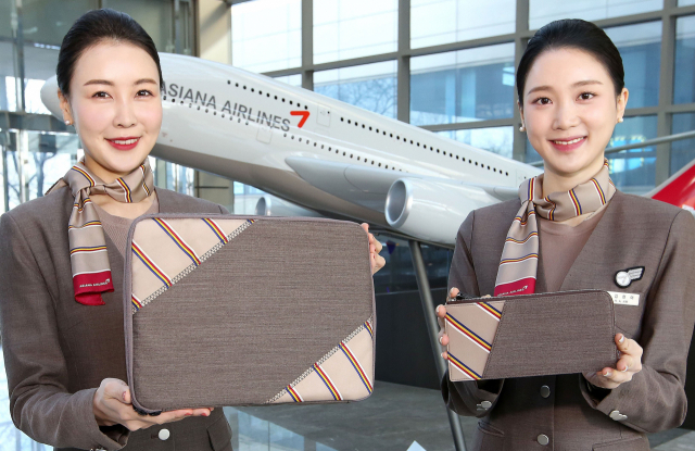 아시아나항공 승무원들이 회수한 유니폼을 이용해 제작한 업사이클링 제품인 태블릿 파우치를 소개하고 있다./사진 제공=아시아나항공