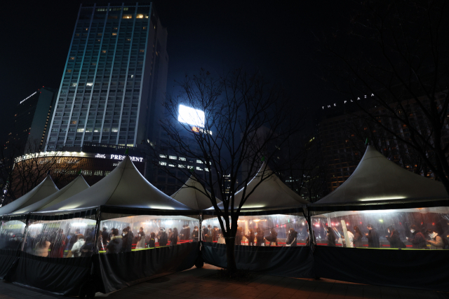 국내 오미크론 변이 확진자가 폭발적으로 증가하고 있는 27일 저녁 서울광장에 마련된 선별진료소를 찾은 시민들이 줄을 서서 검사를 기다리고 있다./연합뉴스