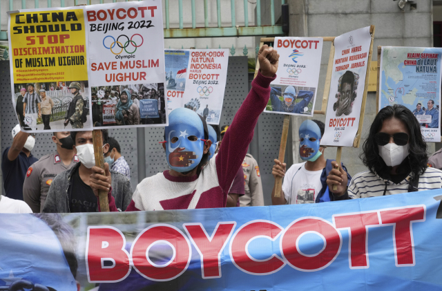가면을 쓴 학생 운동가들이 14일 인도네시아 자카르타의 주인도네시아중국대사관 앞에서 신장 지역의 인권 침해를 이유로 2022 베이징 동계올림픽을 취소하라고 요구하고 있다. /AP연합