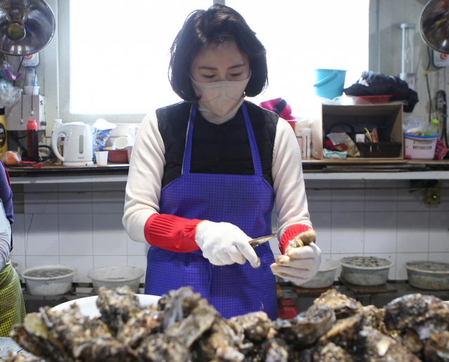 더불어민주당 이재명 대선 후보 부인 김혜경 씨가 1박 2일 경남 방문 마지막 일정으로 27일 통영 굴 작업장에 방문해 굴 까기 작업 체험을 하고 있다. /연합뉴스